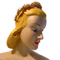 A vintage-style gold tiara with leaf-like detailing, shown on a blonde mannequin head against a plain white background.
