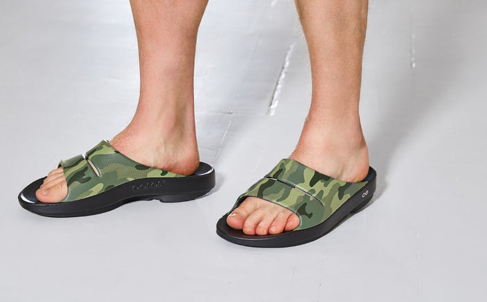 Green camouflage sandals worn by a person on a white background | lifestyle